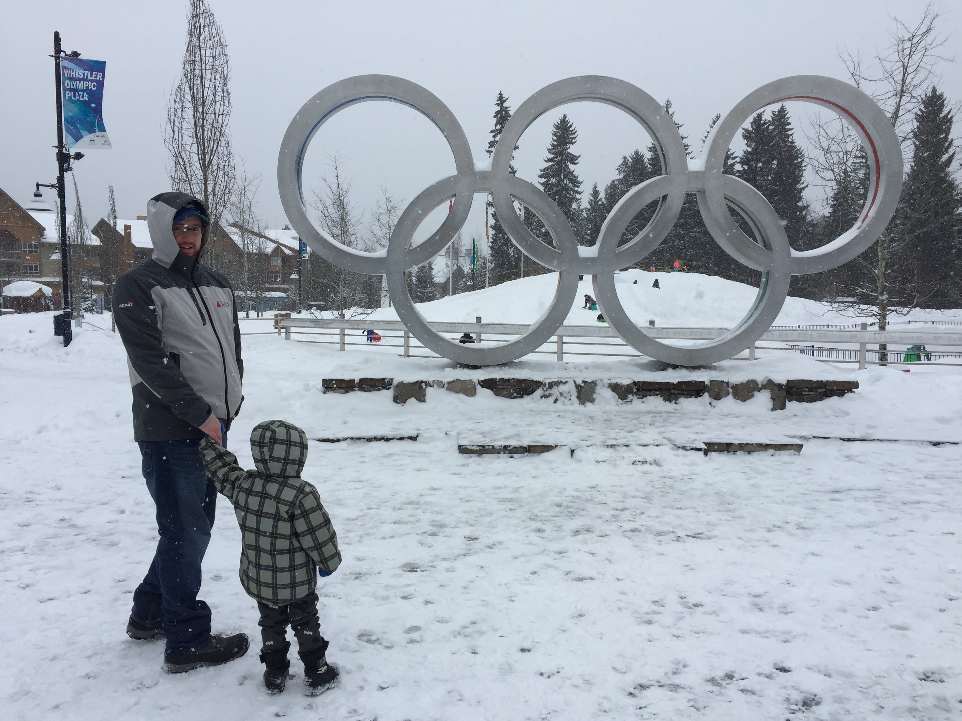 Man and Son in Snow in front of Olympic Rings in Whistler Village
